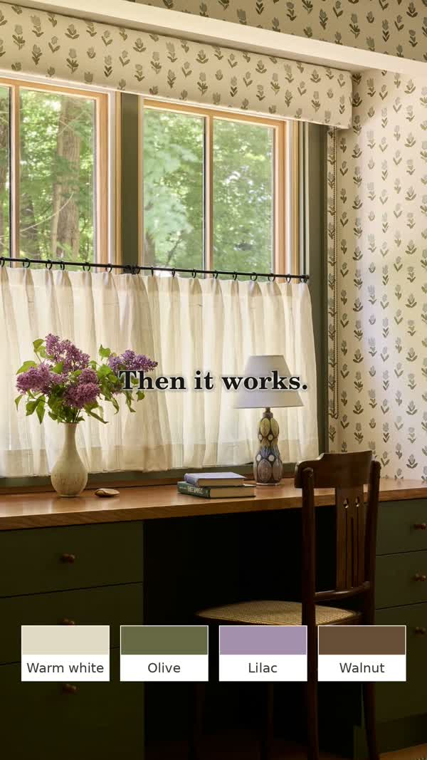 Illustrative dining space with warm white curtains, olive cabinetry, walnut-coloured furniture and lilac flowers.